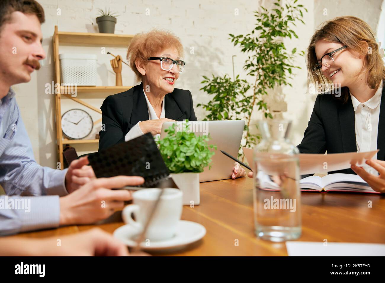 Friendly atmosphere at business gathering. Mixed ages people talking, working with colleagues at loft style office space, indoors. Stock Photo