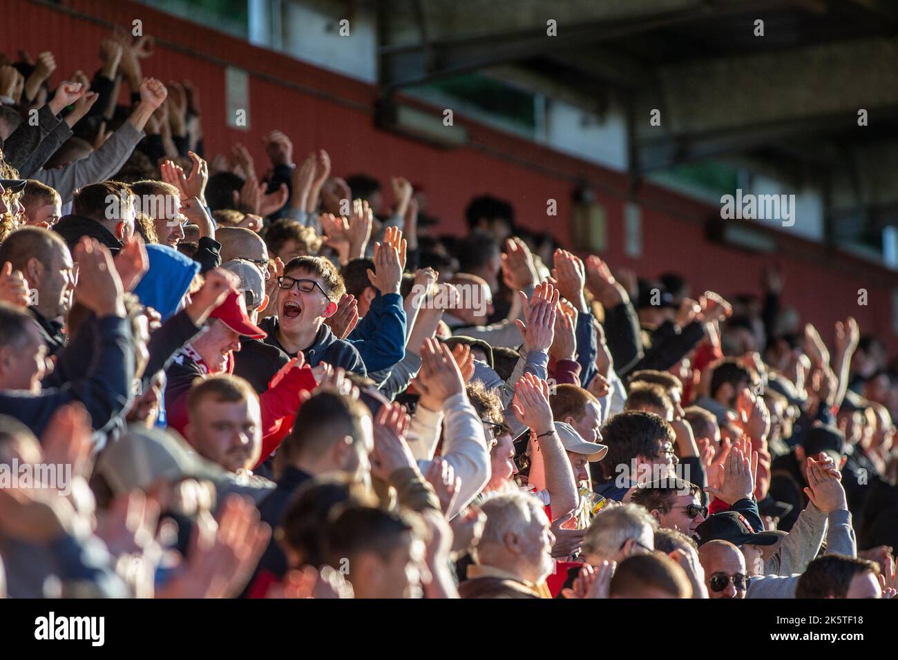 Football / soccer fans and spectators on standing terrace at stadium applauding and clapping during game. Stock Photo