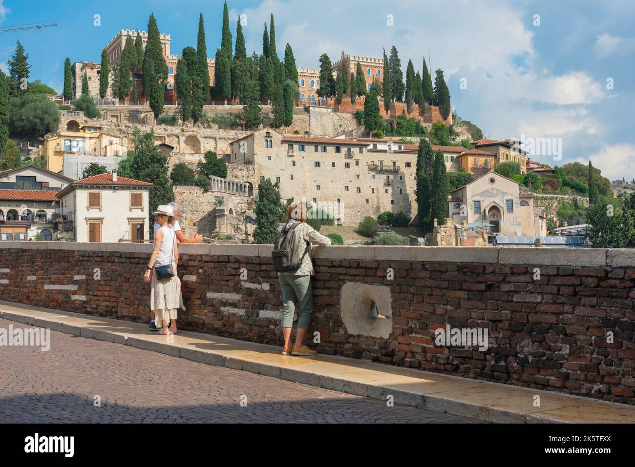 Ponte di Pietra bridge, view of people standing on the Ponte Pietra and looking towards San Pietro Hill on the north bank of the Adige, Verona, Italy Stock Photo