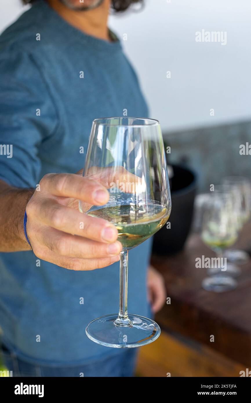 Man hand holding out a wine glass in a celebration. Closeup. Stock Photo