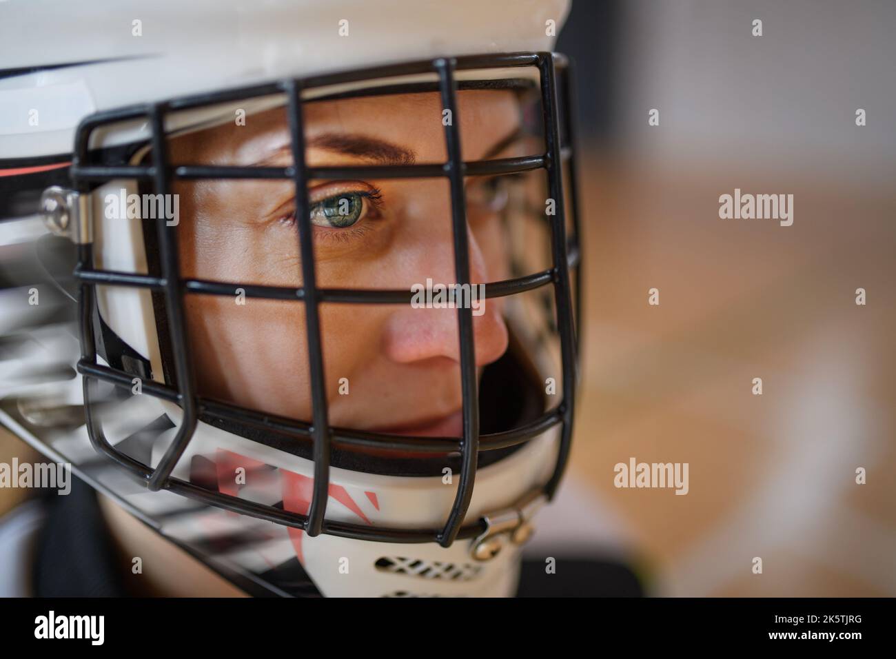 Close-up of woman floorball goalkeeper in helmet concetrating on game in gym. Stock Photo