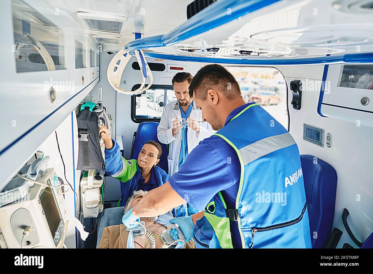 Paramedics with portable defibrillator in attempt to revive male patient inside ambulance