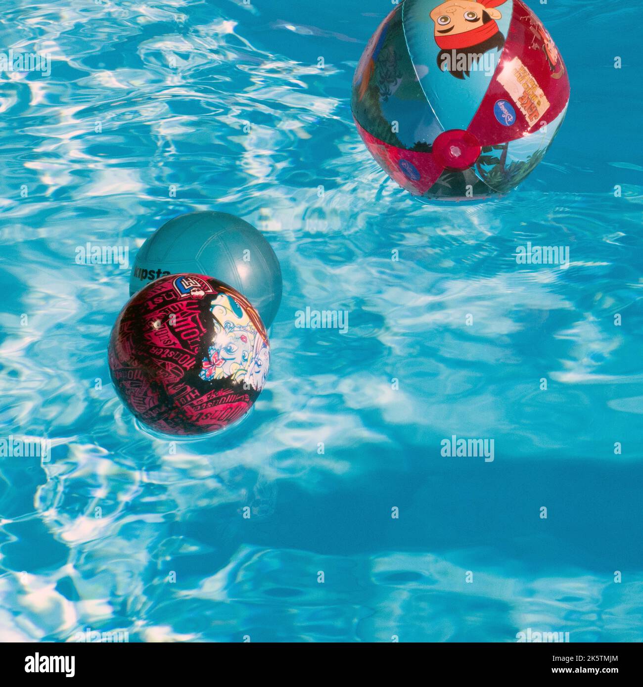 three inflatable balls floating on swimming pool surface Stock Photo