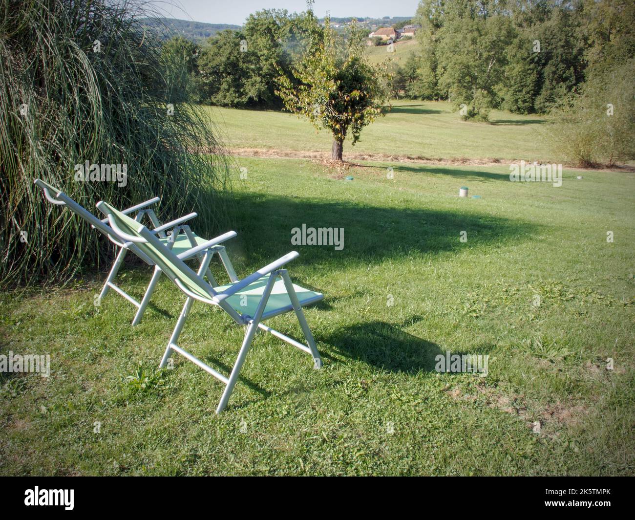 two empty garden chairs overlooking sloping meadow dordogne france Stock Photo
