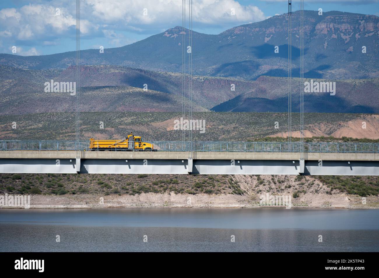 A single yellow dump truck driving across the Roosevelt Lake Bridge Stock Photo
