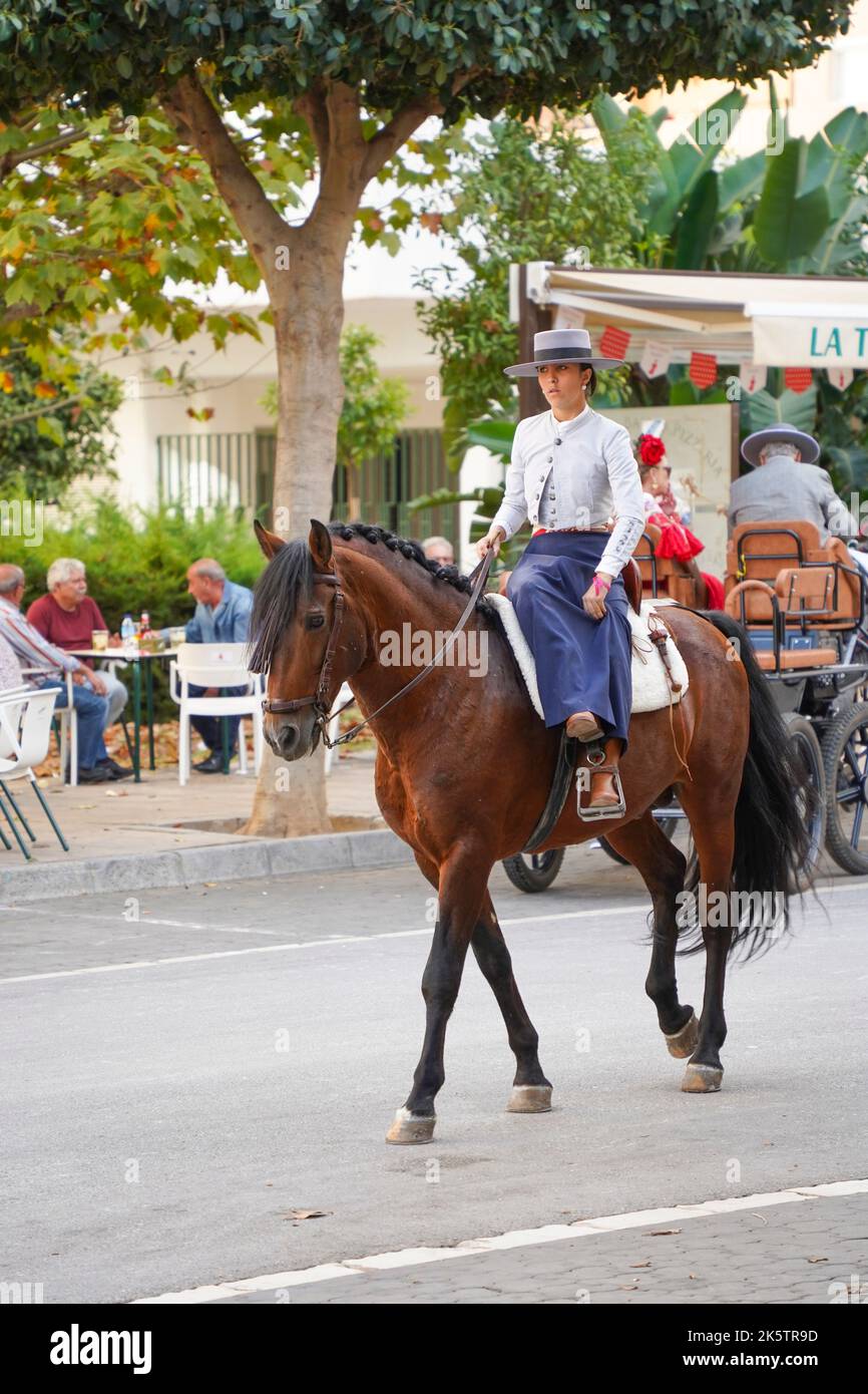 Spanish woman dressed in traditional costume, horse riding during Feria, of Fuengirola, Andalucia, Spain. Stock Photo