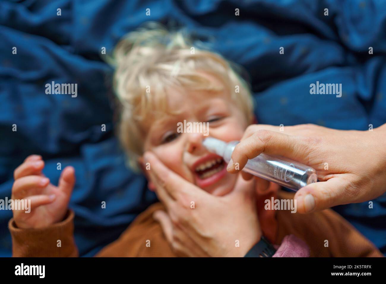 Close-up of parent holding his son and using snot extractor. Stock Photo