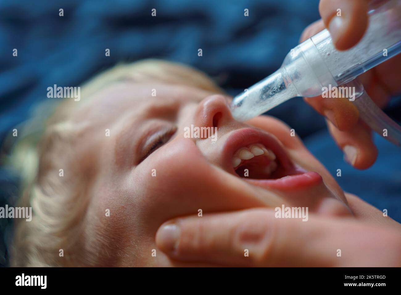 Close-up of parent holding his son and using snot extractor. Stock Photo