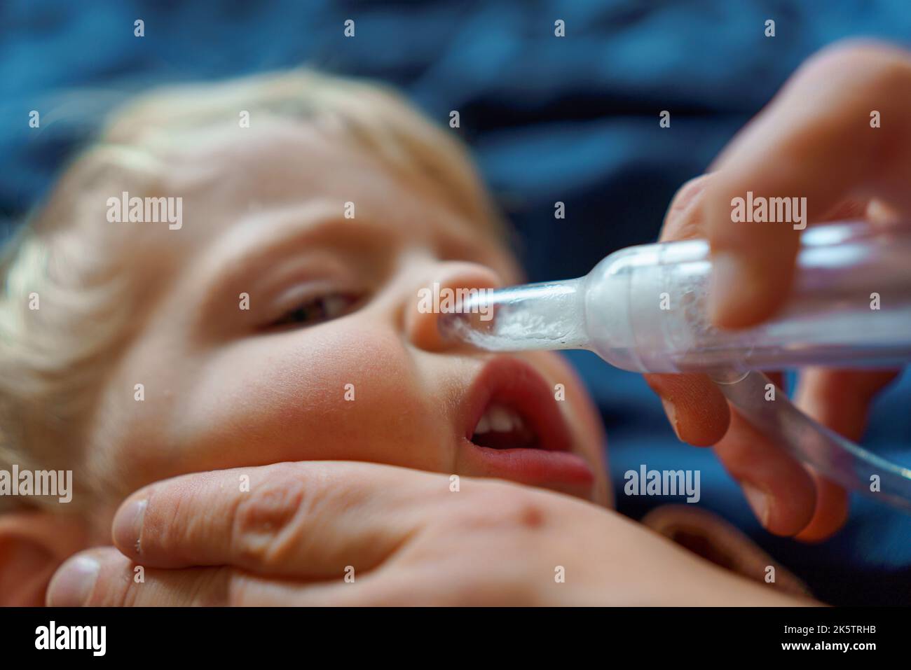 Close-up of parent holding his son and using snot extractor. Stock Photo