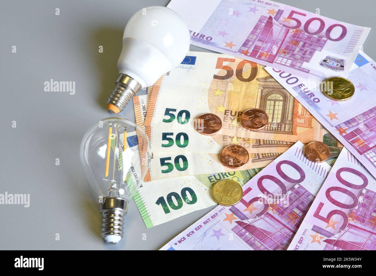 Electric plug, euro money banknotes and cents with light bulb over grey