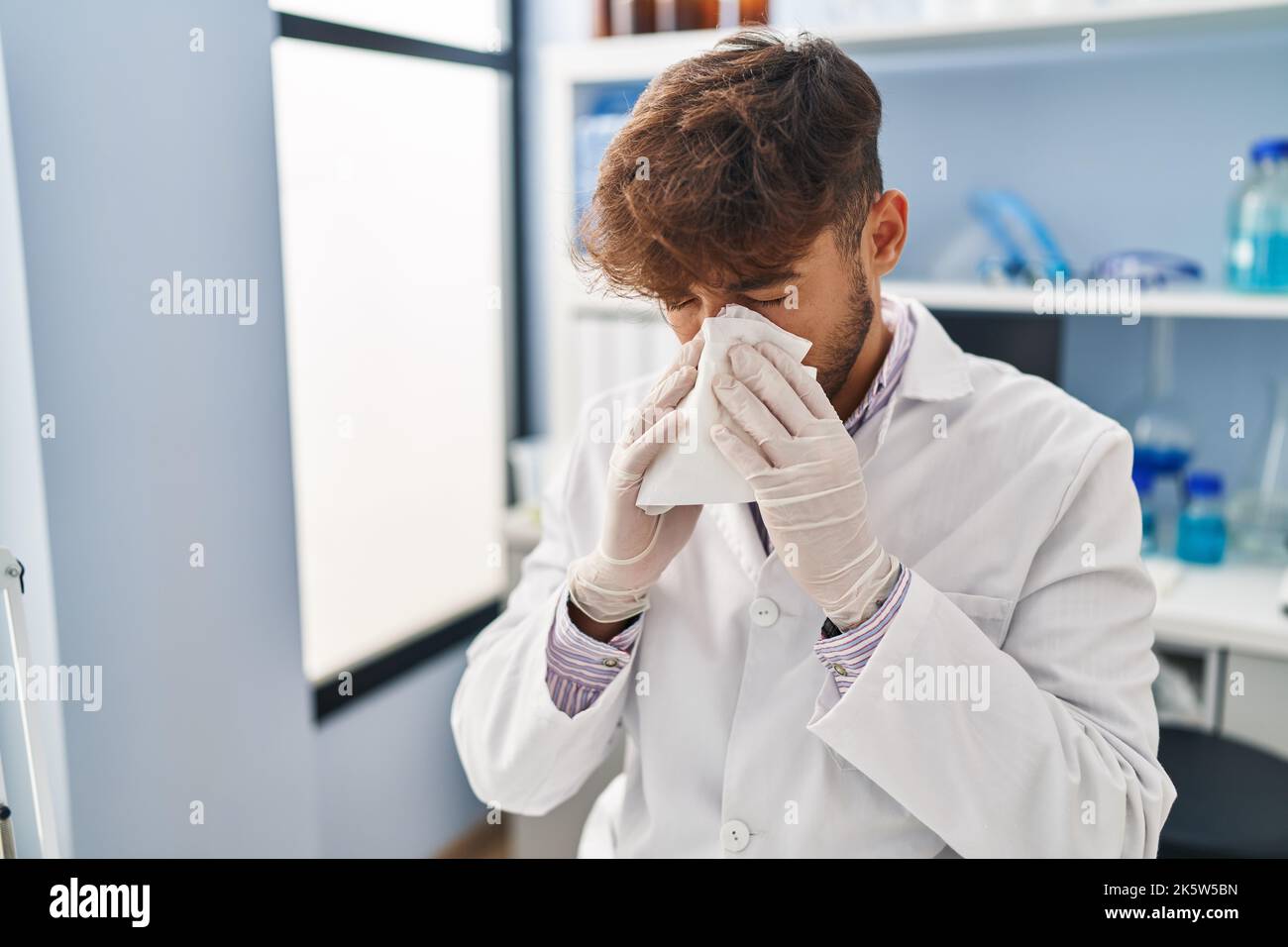 Young arab man scientist using napkin at laboratory Stock Photo