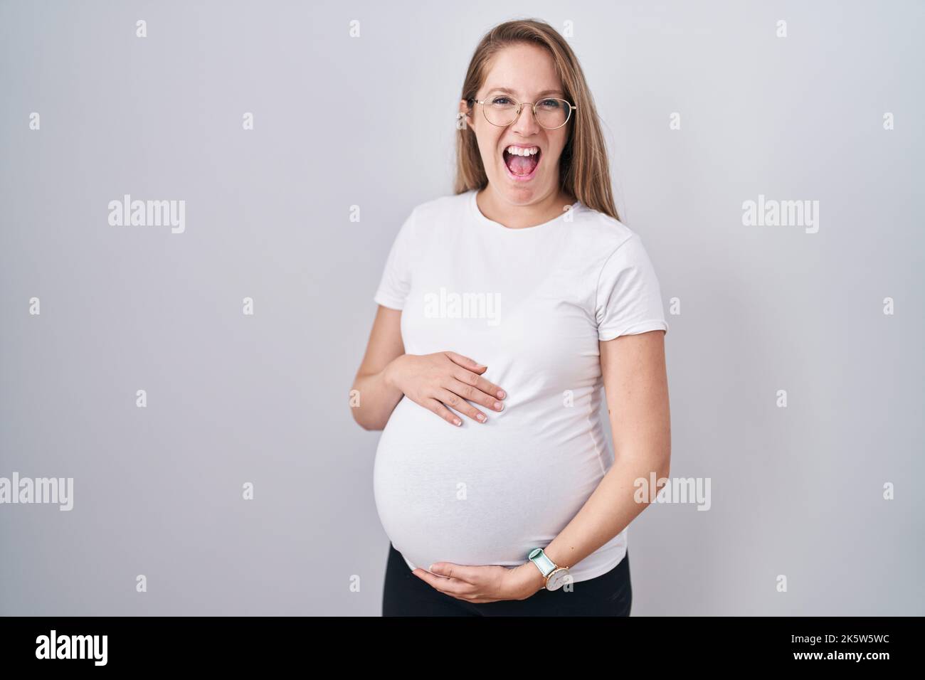 Young pregnant woman expecting a baby, touching pregnant belly smiling