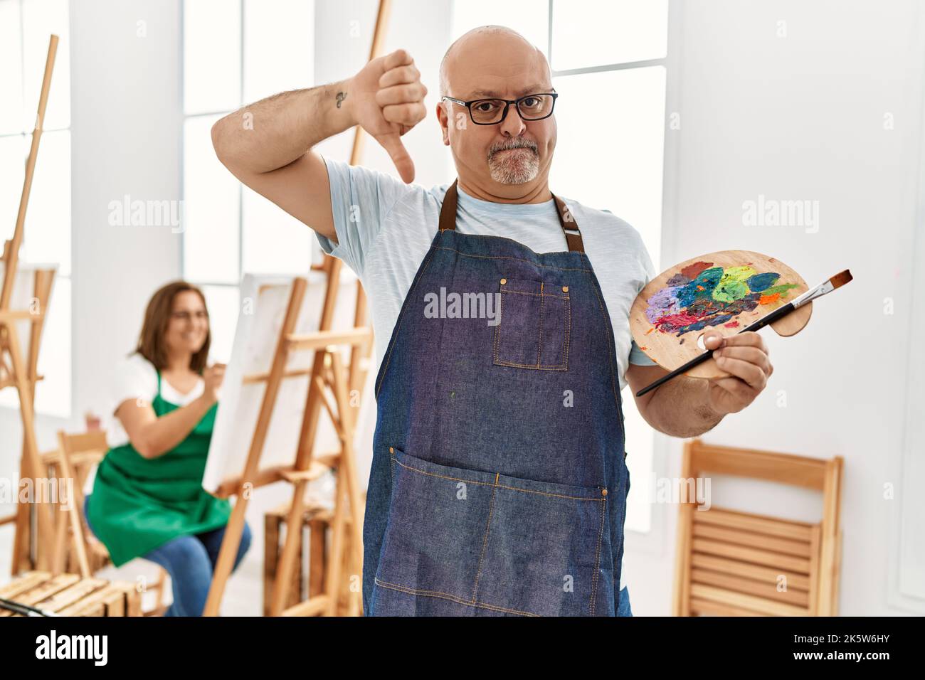 Middle age hispanic man at art studio with angry face, negative sign ...