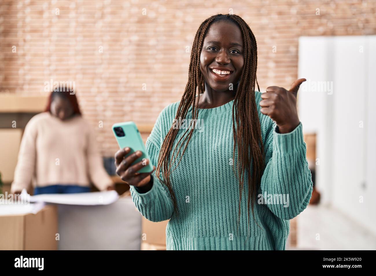 African woman using smartphone at new home smiling happy and positive ...