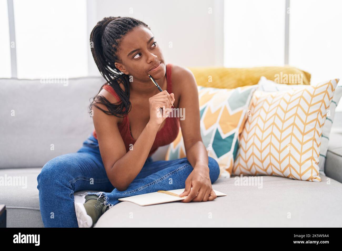 African american woman writing on notebook sitting on sofa at home ...