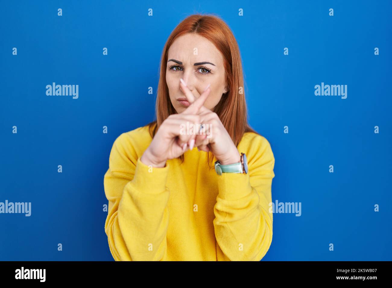 Young woman standing over blue background rejection expression crossing ...