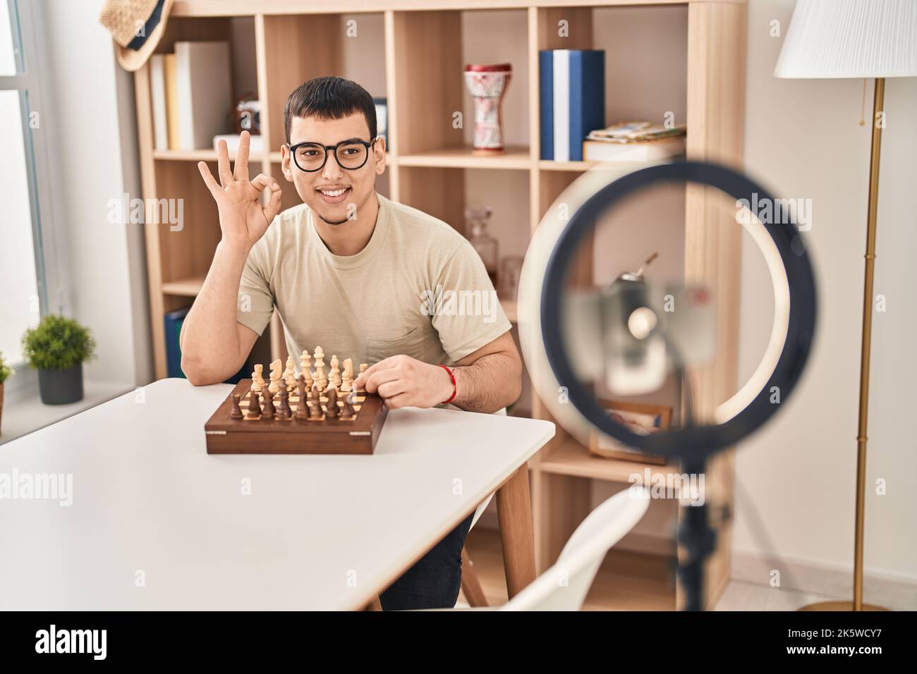 Young arab man doing chess tutorial doing ok sign with fingers, smiling friendly gesturing excellent symbol Stock Photo