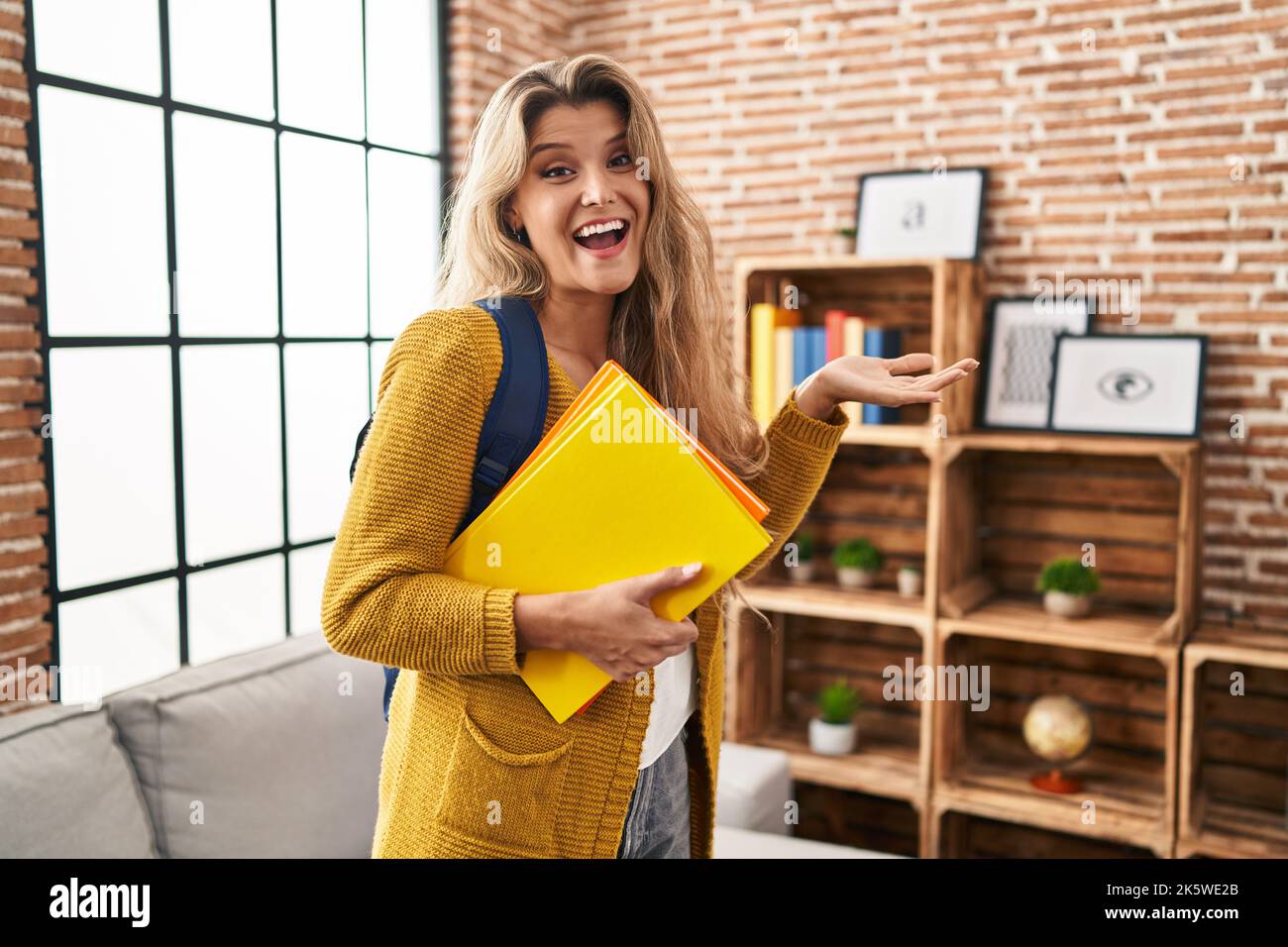 Young woman wearing student backpack and holding books celebrating ...