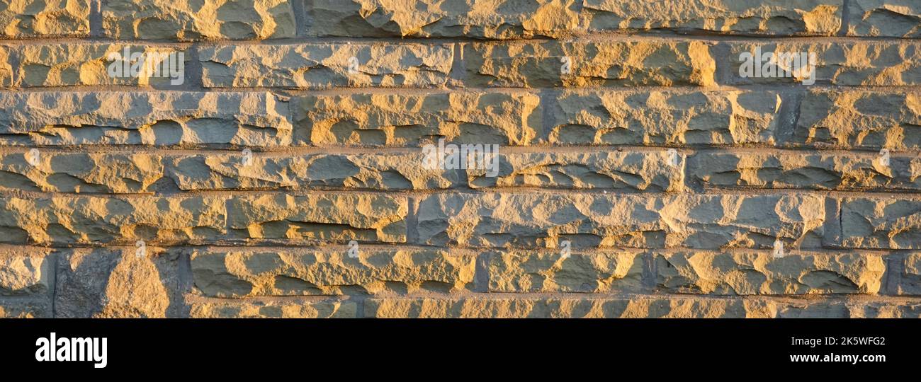 Sunshine on natural York stone blocks cut & dressed from redundant London paving slabs reused in external skin of house cavity wall Essex England UK Stock Photo