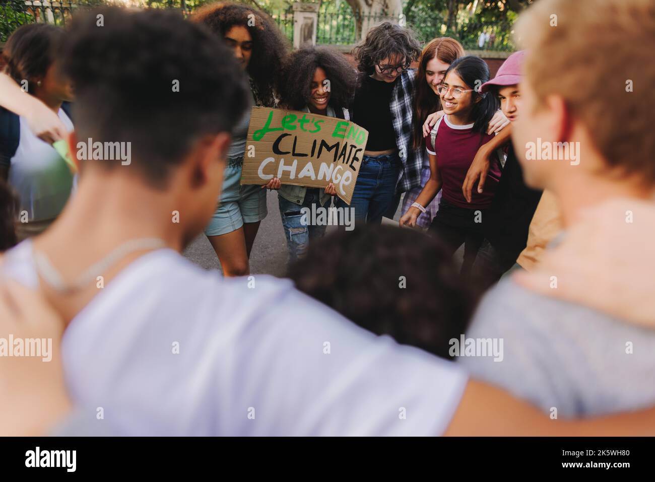 Group of multicultural youth activists standing together in a circle at a climate change demonstration. Generation Z youngsters joining the global cli Stock Photo