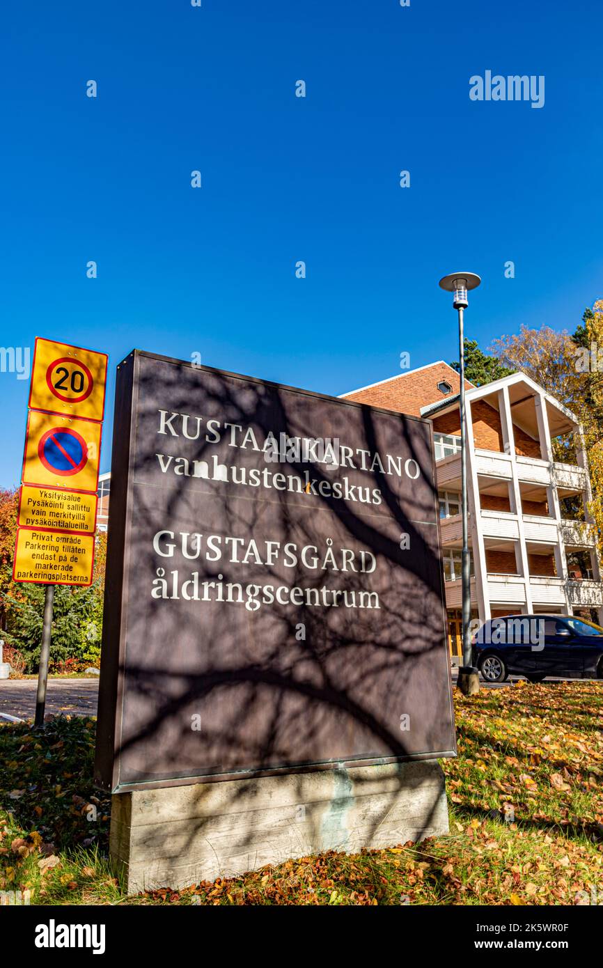 Sign at entrance to the Kustaankartano senior centre area in Oulunkylä, Helsinki, Finland. In the background, building C. Autumn leaves on the ground. Stock Photo