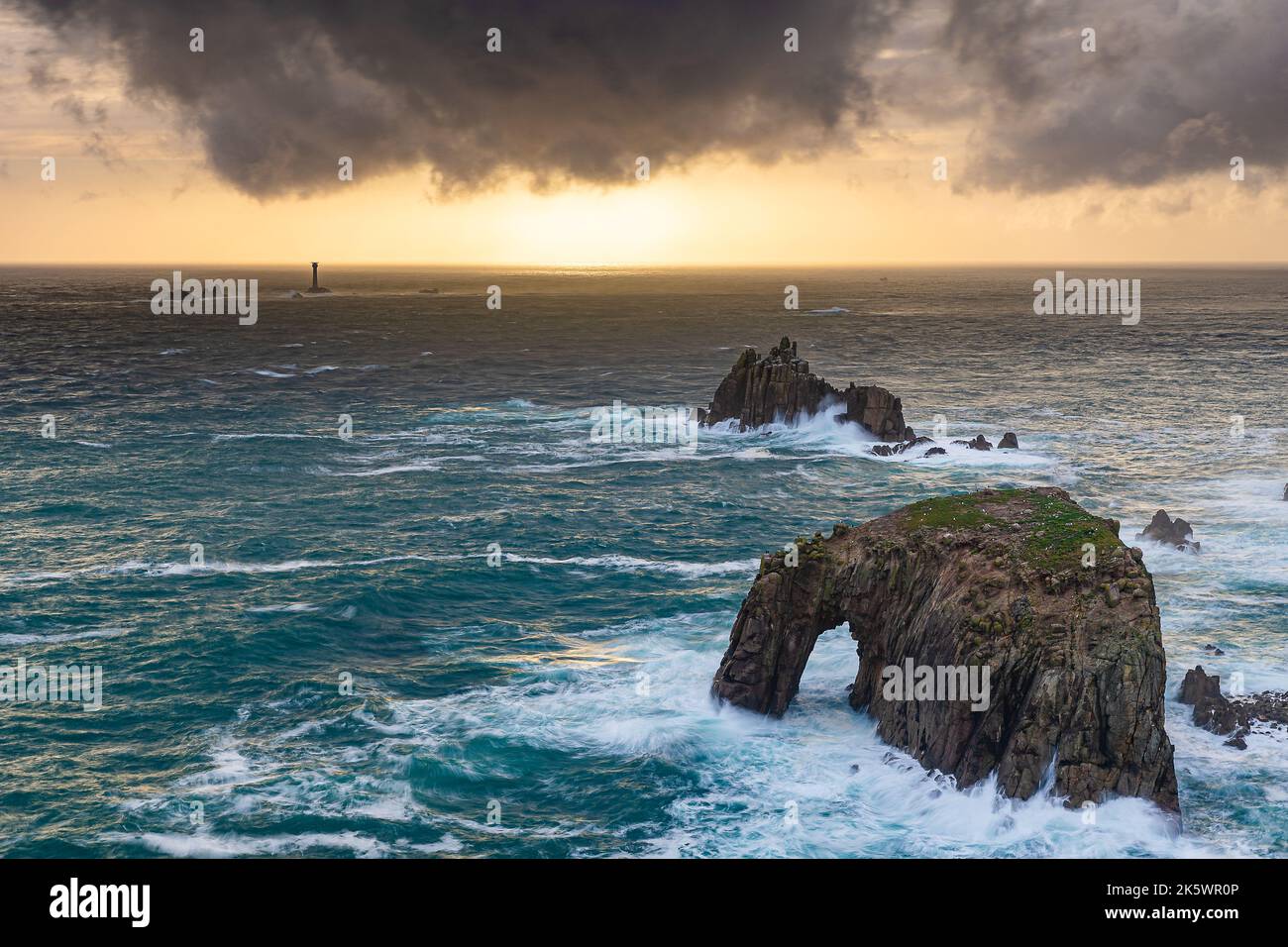 Enys Dodnan Arch and Longships Lighthouse, Cornwall, United Kingdom Stock Photo