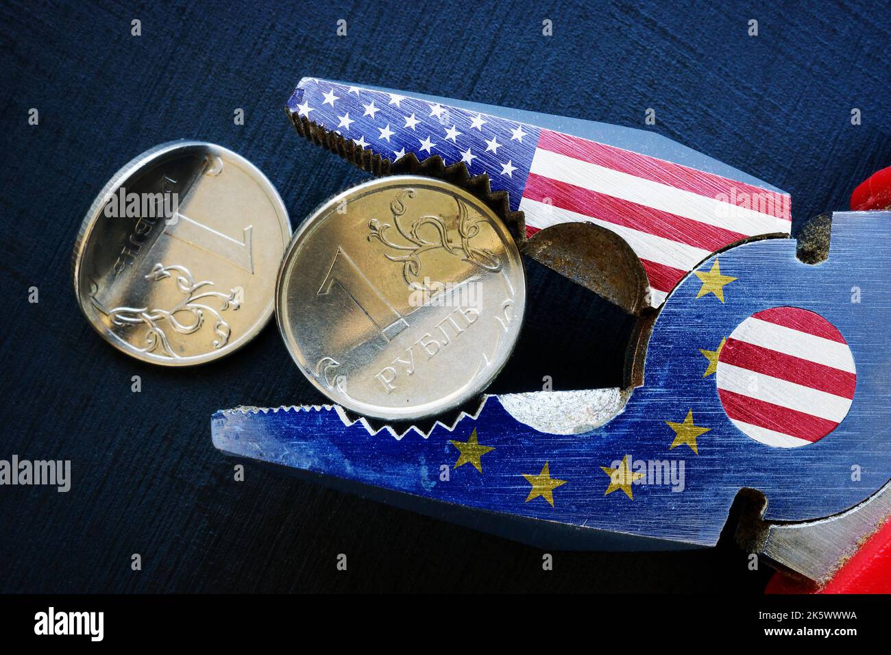 Pliers with US and EU flags bend the Russian ruble. Economic sanctions against Russia. Stock Photo
