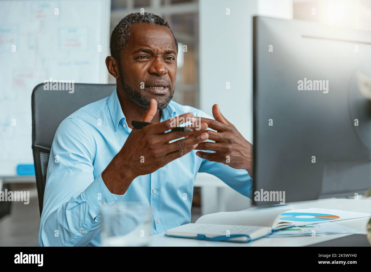 Busy african businessman making videocall to client while sitting in modern office Stock Photo