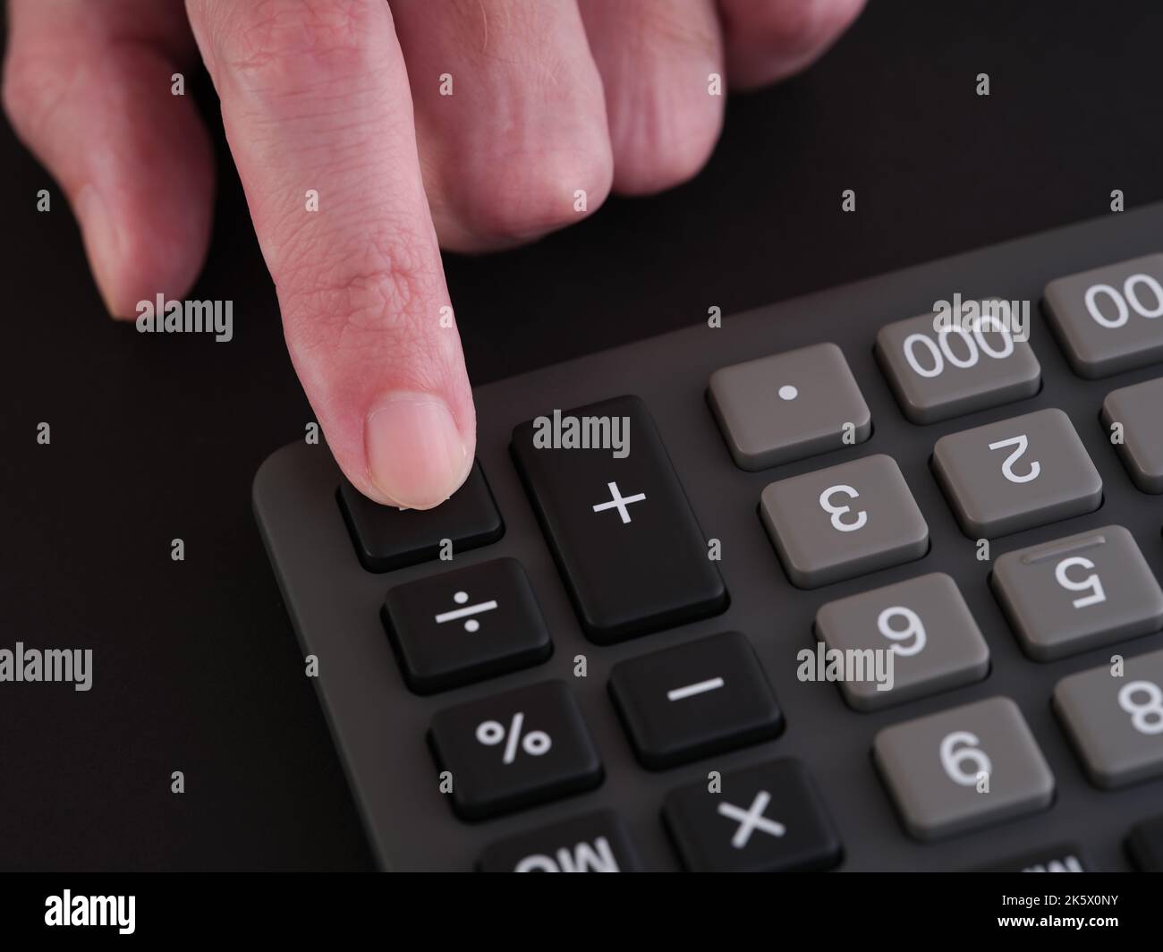 A man pressing the equals button on a calculator. Close up. Stock Photo