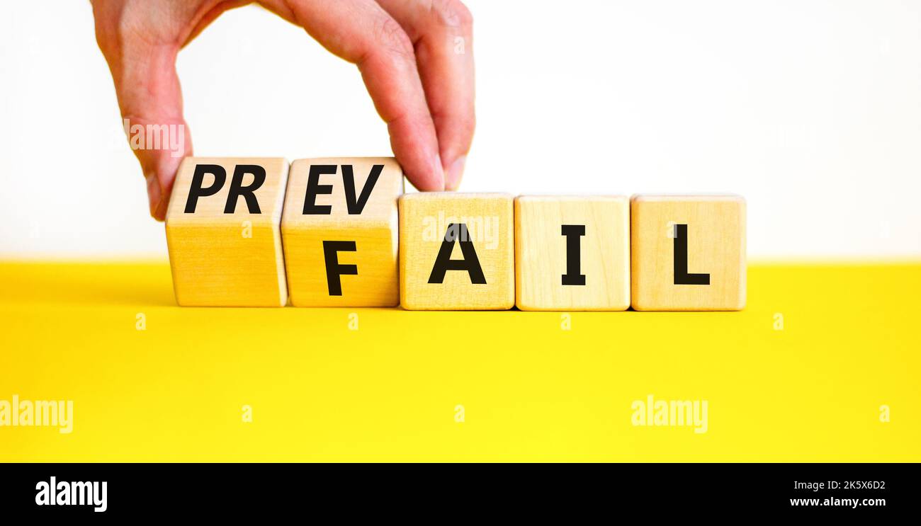Prevail or fail symbol. Concept words Prevail or Fail on wooden cubes. Businessman hand. Beautiful yellow table white background. Business prevail or Stock Photo