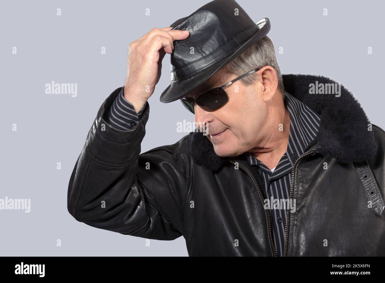 handsome elderly man with sunglasses, hat and black leather jacket Stock Photo