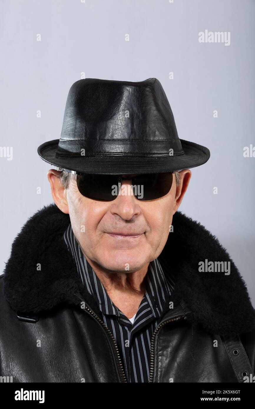handsome elderly man with sunglasses, hat and black leather jacket Stock Photo