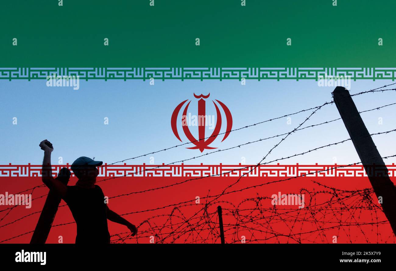 Person throwing rock over barbed wire fence with flag of Iran in background. Protest, protester, student, Iran... concept Stock Photo