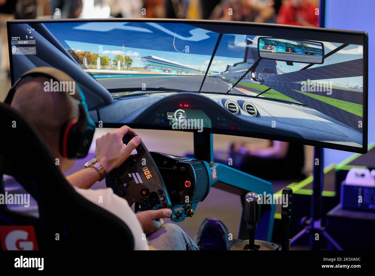 Poland, Poznan - October 09, 2022: Person playing realistic car racing simulator. An event related to computer games and entertainment. Back view. Stock Photo