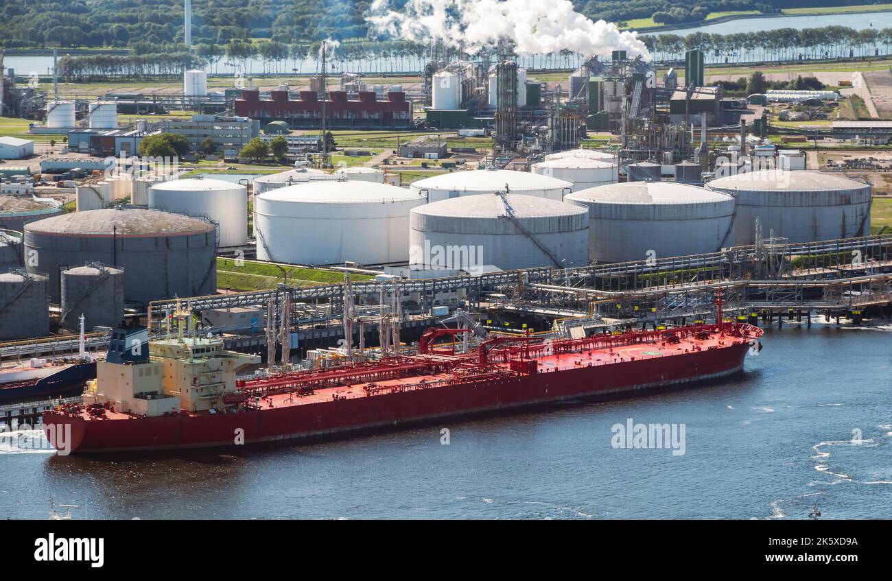 Oil tanker moored an oil terminal with fuel storage silos in an industrial port Stock Photo