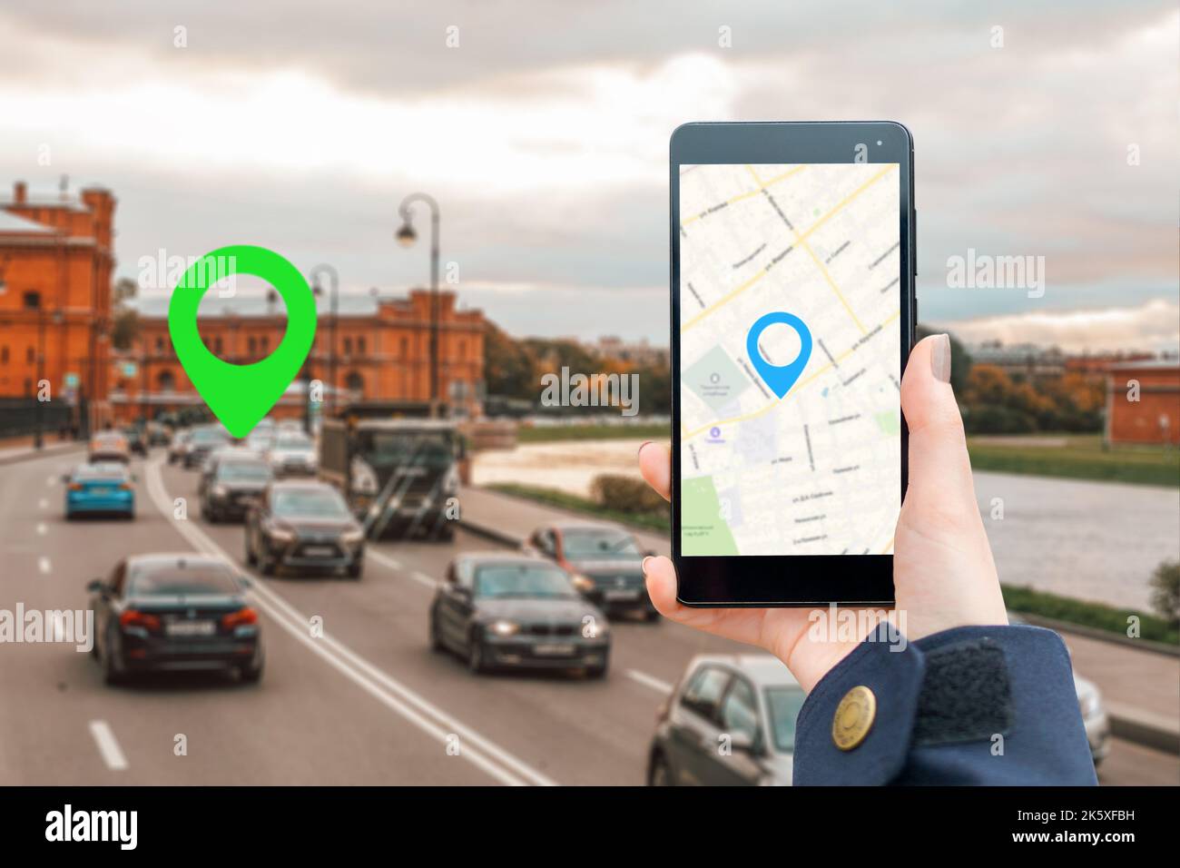 A woman's hand in a jacket holds a smartphone with an online map app ...