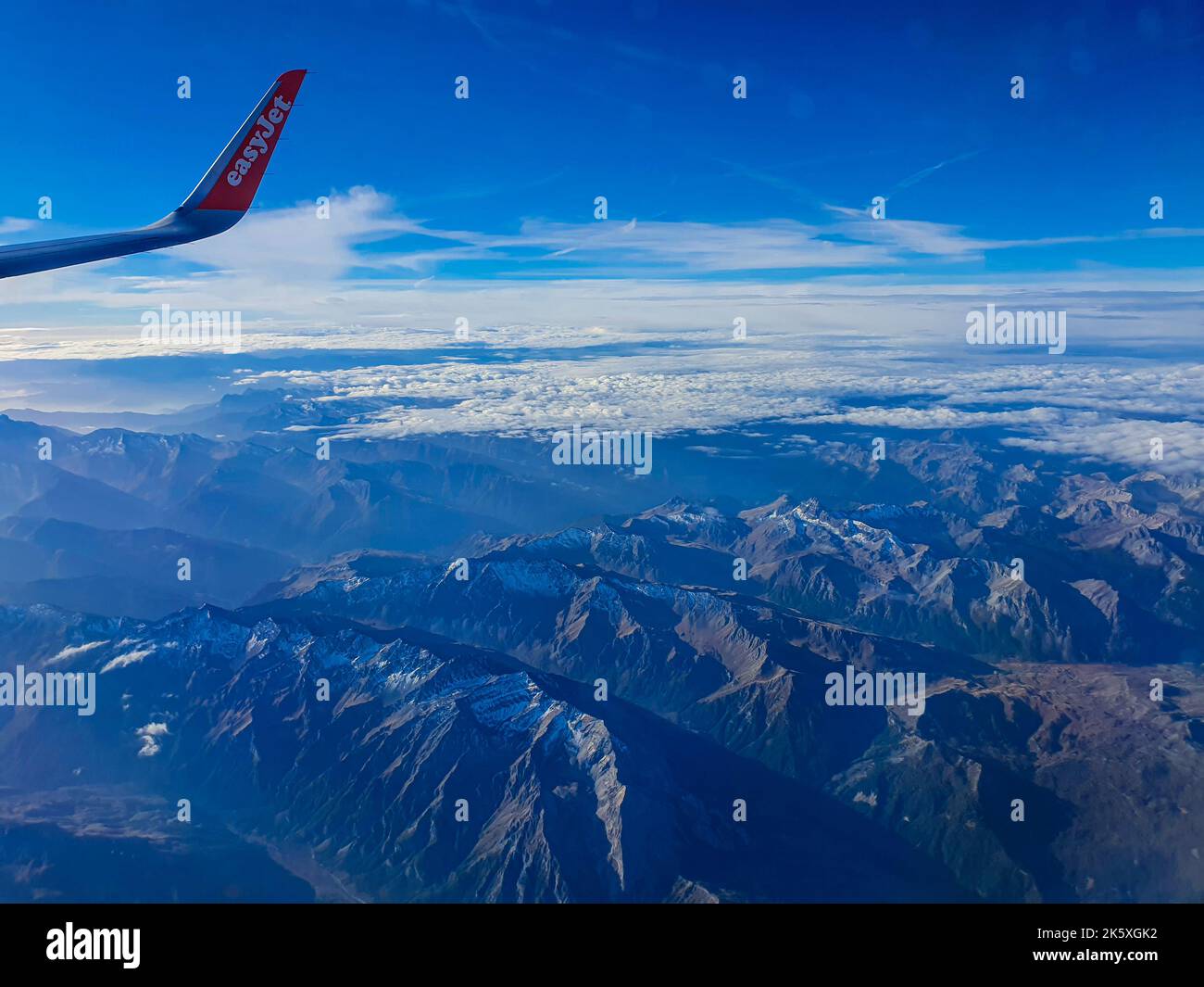 The Alps from the plane with a scattering of snow and cloud Stock Photo ...