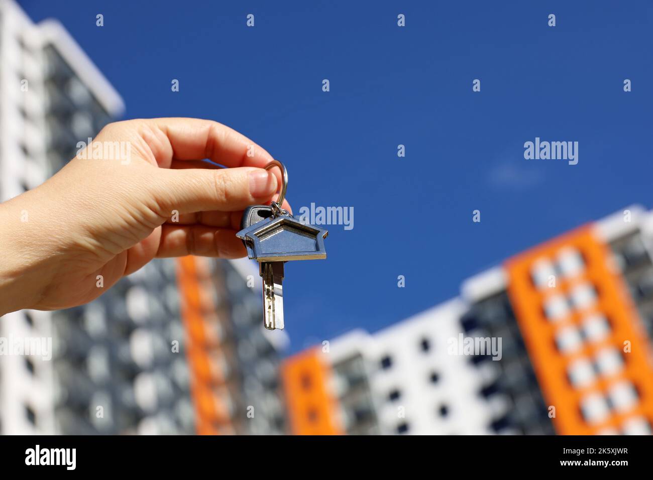 Real estate agent, home keys in female hand on background of new