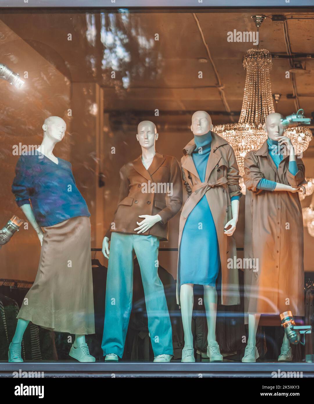 Female mannequins in shop window with demi-season clothing, street reflection. Shopping Stock Photo