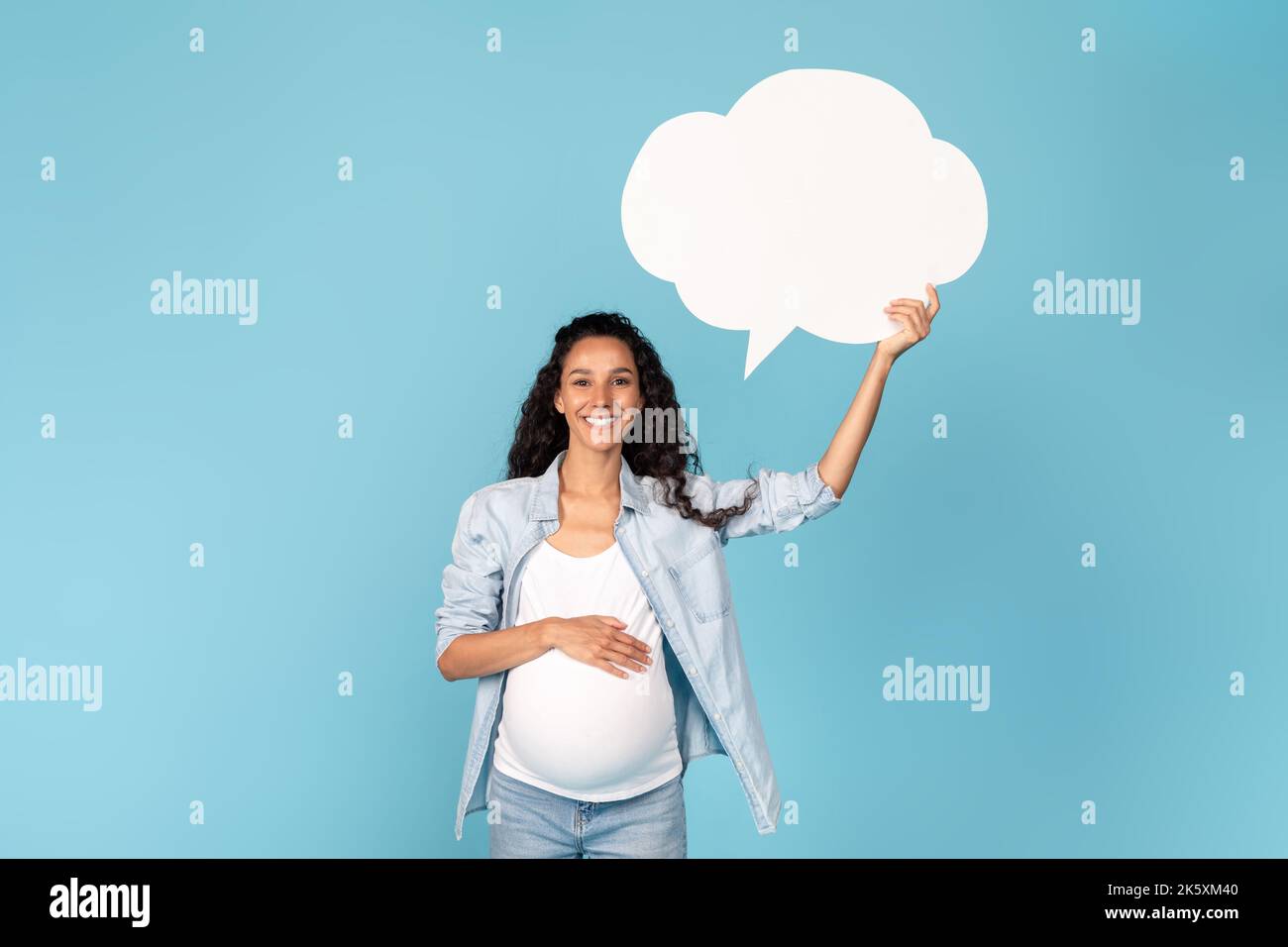 Happy millennial pregnant arab woman with belly holding abstract cloud buble with copy space Stock Photo