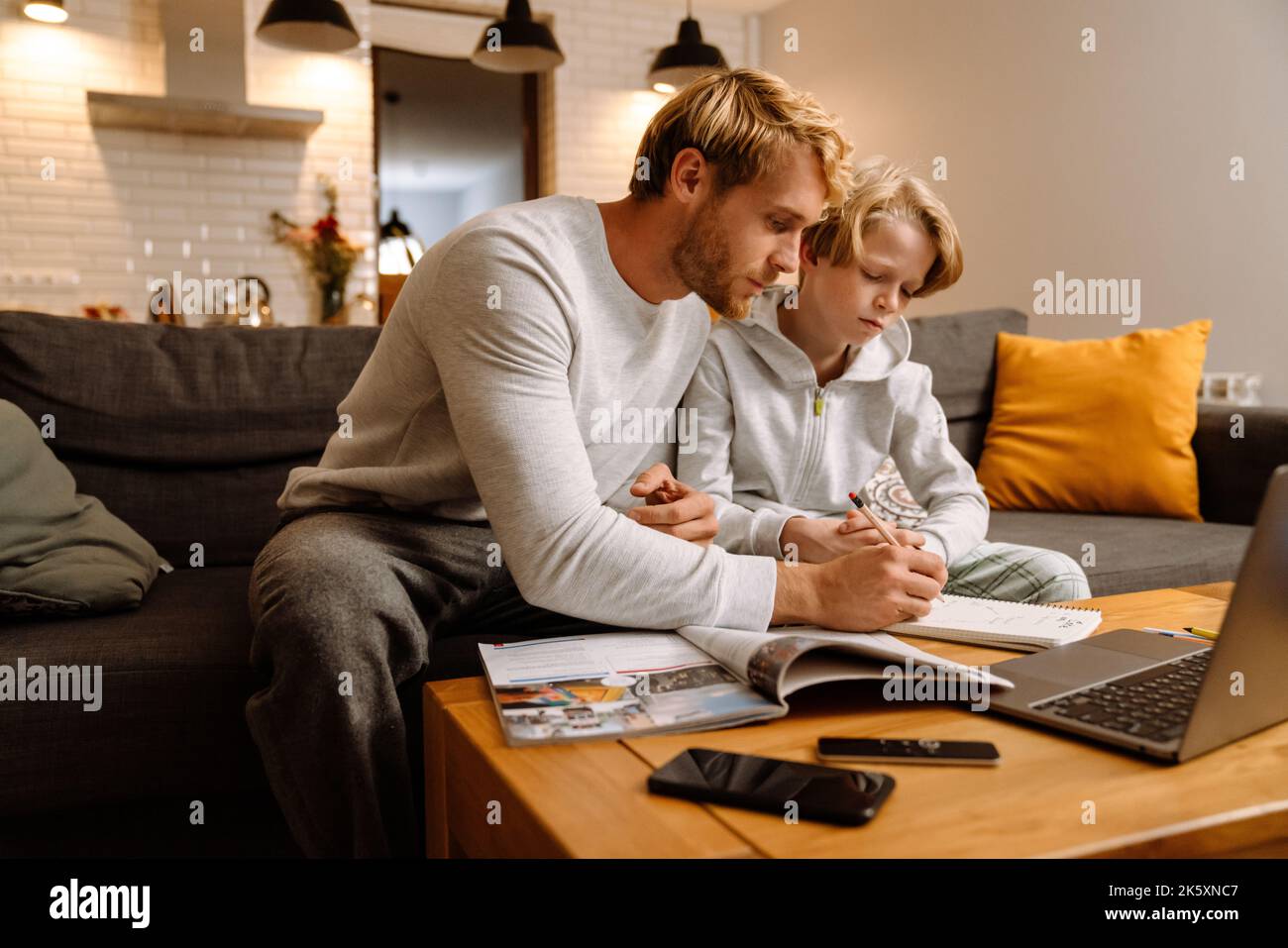 Ginger boy using laptop while doing homework with his father at home Stock Photo