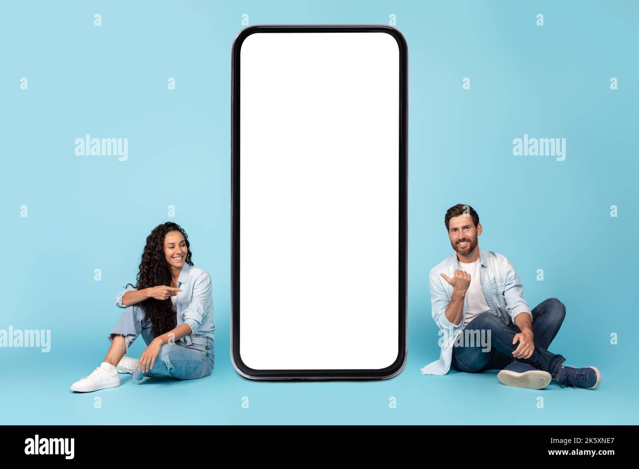 Cheerful millennial caucasian male and middle eastern lady sit on floor
