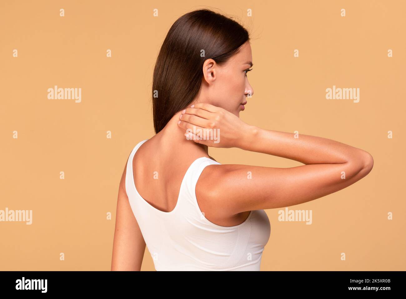 Young woman touching and self massaging her neck, rubbing skin