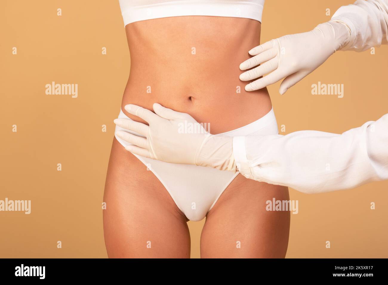 Making perfect body. Lady getting consultation at plastic surgery clinic, closeup view of abdomen and doctor's hands Stock Photo