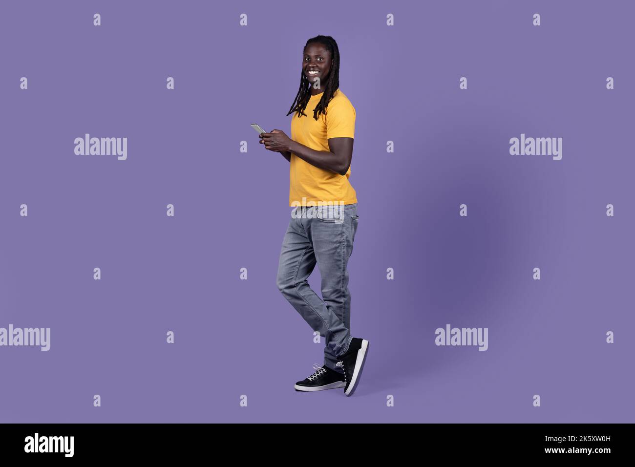 Cool african american guy using cell phone on purple Stock Photo