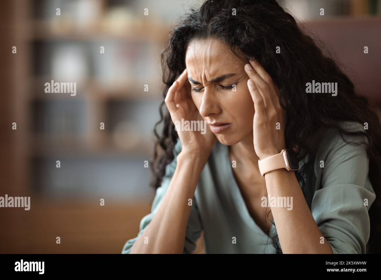 Upset young woman suffering from headache while working Stock Photo