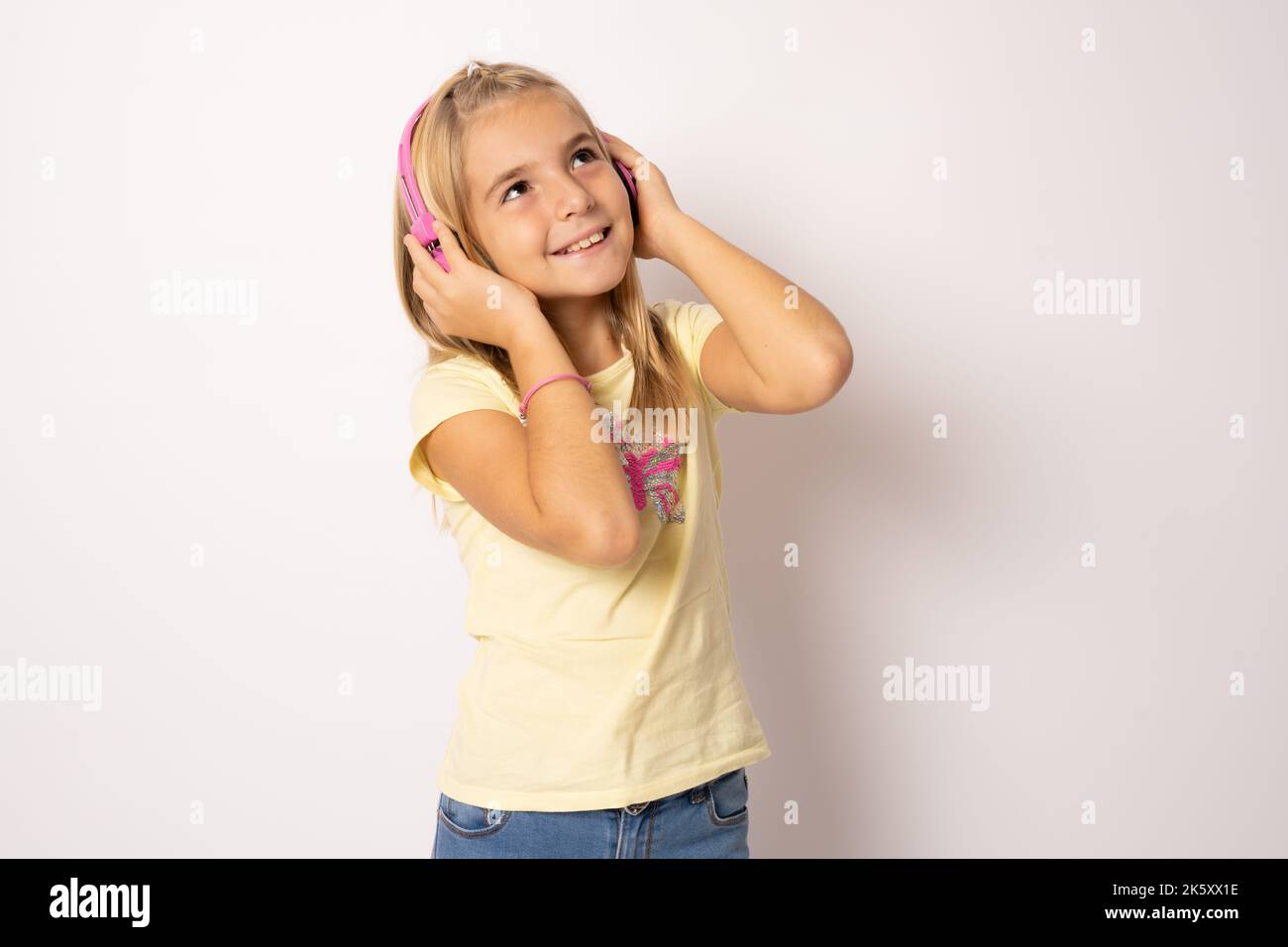 Photo Portrait Of Little Girl Smiling Touching Headphones Listening To photo-portrait-of-little-girl-smiling-touching-headphones-listening-to