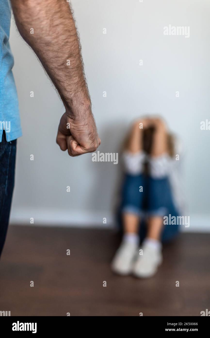 Sad middle aged european woman covering head with hands, suffering from beating by aggressive man with fist Stock Photo