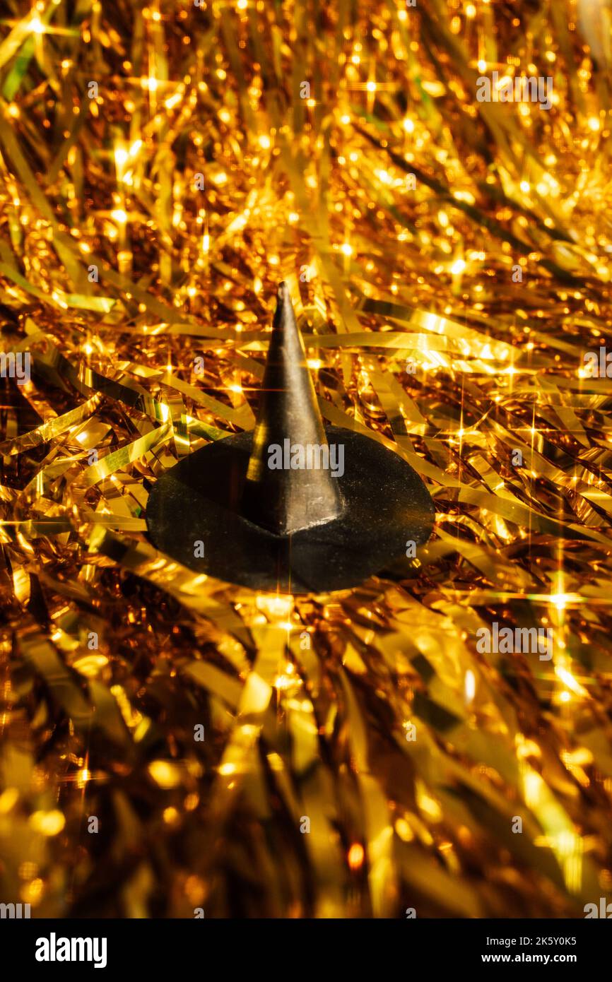 small black witch hat on sparkling gold metallic tinsel backdrop Stock