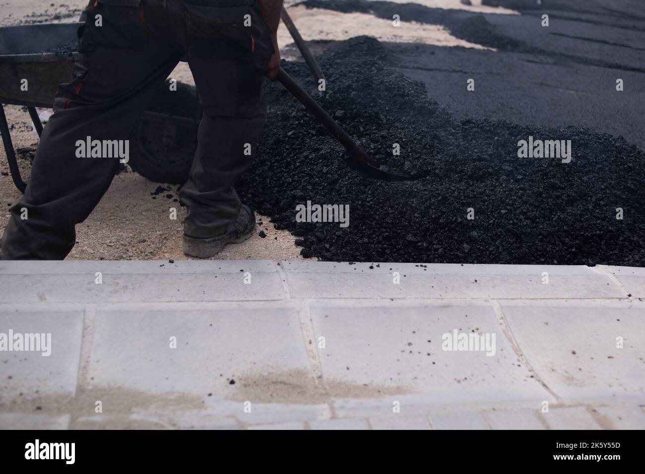 Asphalt is unloaded from a wheelbarrow. The rear part of the asphalt is ...